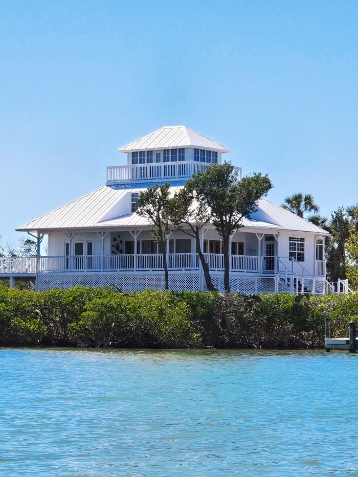 A picturesque white house with unique architecture by the waterfront.