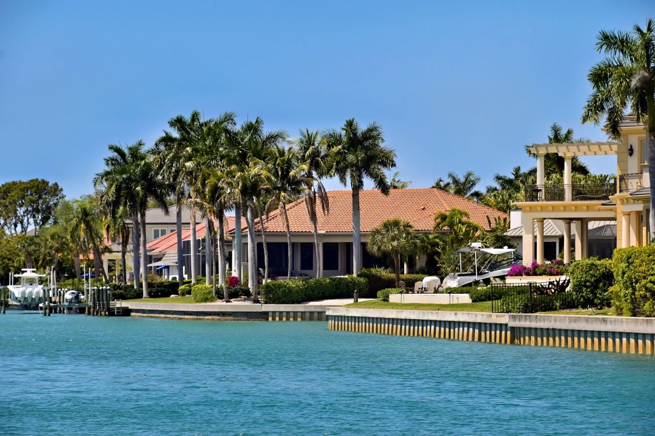 Scenic view of luxury waterfront villas and palm trees under a clear blue sky.